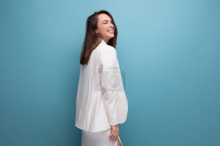 Téléchargez les photos : Jeune femme d'affaires de mode en robe blanche et veste posant sur fond studio avec copyspace. - en image libre de droit
