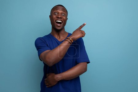 Téléchargez les photos : 30 ans Américain gars dans un T-shirt décontracté pointe son doigt vers l'offre promotionnelle. - en image libre de droit