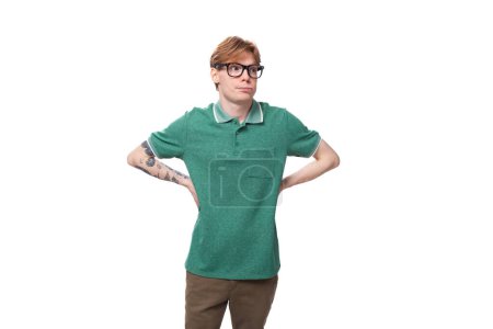 Photo for Young european red-haired man with glasses dressed in a green t-shirt posing on a white background. - Royalty Free Image