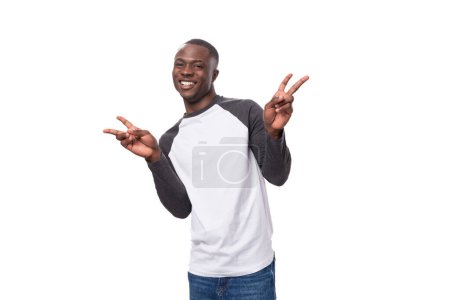 Téléchargez les photos : Jeune homme africain heureux charmant avec coupe de cheveux courte habillé en pull d'été à manches longues. - en image libre de droit
