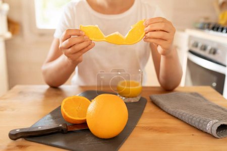 Foto de Una naranja jugosa fresca brillante en las manos de una mujer en la cocina. - Imagen libre de derechos
