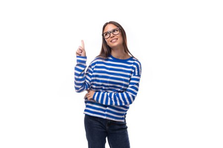 Téléchargez les photos : Portrait d'une jeune femme brune européenne lumineuse et optimiste en chemisier bleu et en jean sur fond blanc avec espace de copie. - en image libre de droit