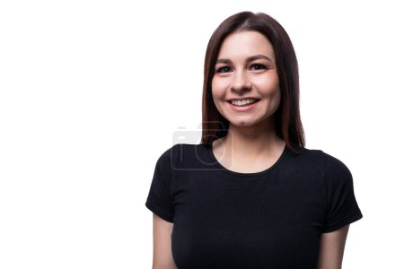 Photo for Positive pretty young brunette woman wearing a black t-shirt on a white background with copy space. - Royalty Free Image