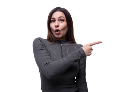 Photo for Young brunette woman pointing her finger to the side in cute surprise. - Royalty Free Image