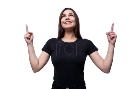 Photo for Positive pretty young brunette woman dressed in a black t-shirt shows her fingers up. - Royalty Free Image