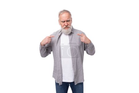 Téléchargez les photos : Bel homme âgé aux cheveux gris dans une chemise est inspiré par une idée sur un fond blanc avec espace de copie. - en image libre de droit