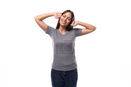 Téléchargez les photos : Jeune femme caucasienne aux cheveux foncés habillée en t-shirt gris décontracté avec espace pour l'impression de logo. - en image libre de droit