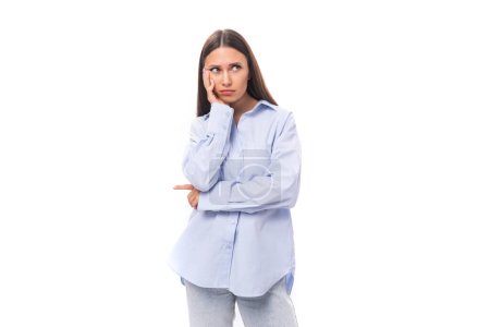 Photo for Young caucasian model woman with dark straight hair dressed in a blue blouse looks upset at the camera. - Royalty Free Image