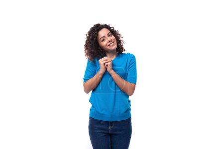 Téléchargez les photos : Authentique mince jeune femme caucasienne avec des boucles habillé d'un t-shirt bleu et jeans. - en image libre de droit