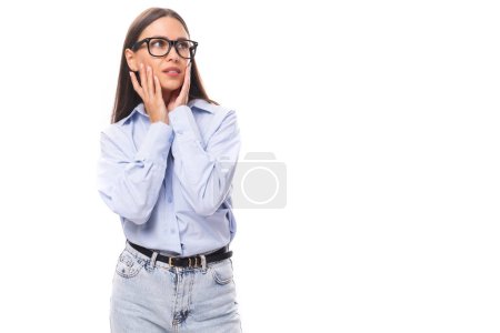 Téléchargez les photos : Attrayant bien entretenu jeune femme caucasienne brune dans des lunettes est habillé d'une chemise bleu ciel sur un fond blanc avec espace de copie. - en image libre de droit