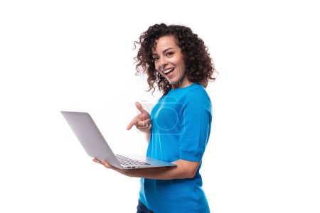 Téléchargez les photos : Jeune femme caucasienne bien entretenue avec des boucles tient un ordinateur portable. Concept de commerce électronique. - en image libre de droit