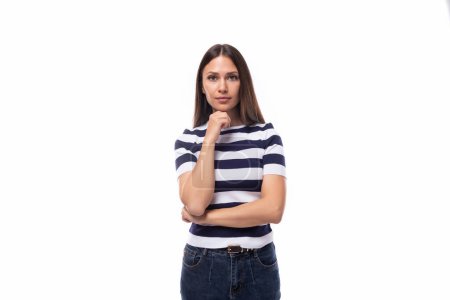 Téléchargez les photos : Jeune brune intelligente dame européenne de construction mince vêtue d'un t-shirt noir et blanc sur un fond blanc avec espace de copie. - en image libre de droit