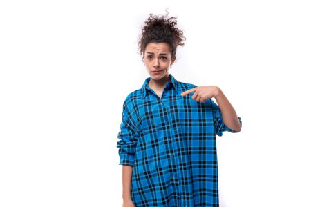 Téléchargez les photos : Une jeune femme brune caucasienne avec ses cheveux réunis dans un chignon est habillée d'une chemise bleue lâche. - en image libre de droit