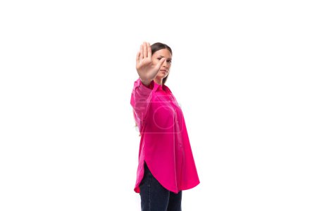 Foto de Retrato de una joven seria con el pelo negro en una camisa de gran tamaño carmesí mostrando gesto de parada de la mano. - Imagen libre de derechos