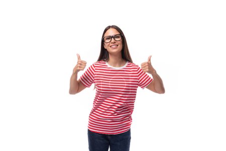 Foto de Joven encantadora morena con gafas vestidas con una camiseta a rayas sobre un fondo blanco con espacio para copiar. - Imagen libre de derechos