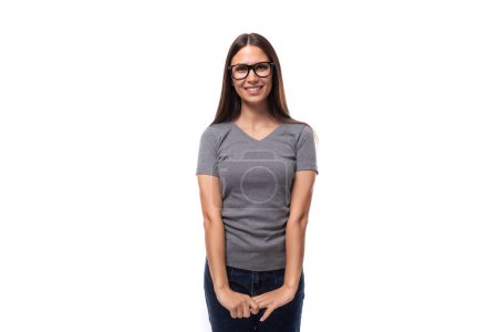 Foto de Mujer promotora joven con gafas vestidas con una camiseta gris en una maqueta de impresión de identidad sobre un fondo blanco con espacio para copiar. - Imagen libre de derechos