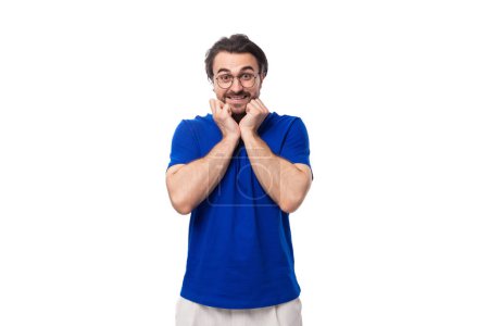 Foto de Joven morena hombre europeo con una barba en una camiseta azul se inspira en una idea sobre un fondo blanco con espacio para copiar. - Imagen libre de derechos
