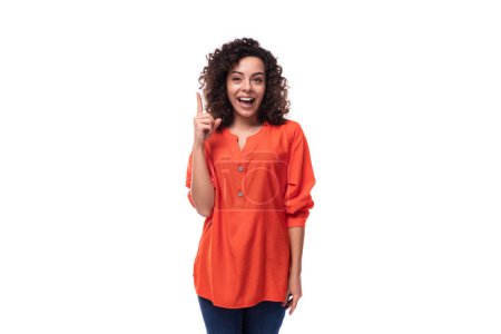 Foto de Joven soñadora mujer de negocios caucásica con cabello ondulado vestida con una blusa naranja sobre un fondo blanco. - Imagen libre de derechos