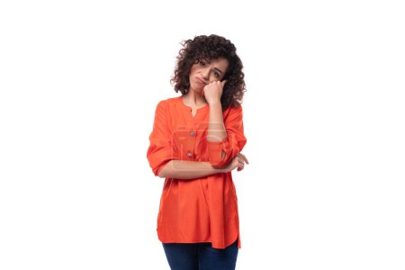 Téléchargez les photos : Jeune femme brune bouclée habillée en chemisier orange se sent fatiguée. - en image libre de droit