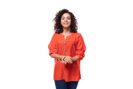 Téléchargez les photos : Portrait d'une jeune femme brune caucasienne aux cheveux bouclés habillée d'une chemise orange. - en image libre de droit