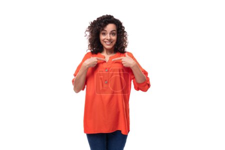 Téléchargez les photos : Jeune femme brune frisée vêtue d'un chemisier orange s'inspire d'une idée. concept de brainstorming. - en image libre de droit