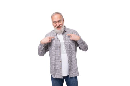 Foto de Lindo abuelo activo inspirado con barba blanca y bigote vestido con camisa a rayas y jeans. - Imagen libre de derechos