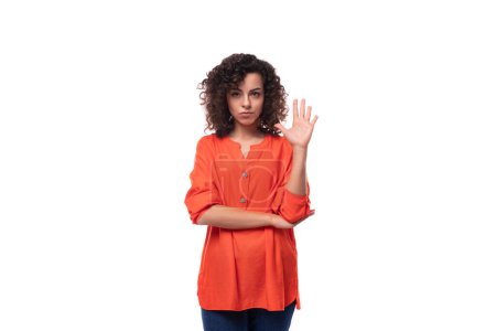 Téléchargez les photos : Jeune femme d'affaires intelligente caucasienne aux cheveux ondulés habillée d'un chemisier orange. - en image libre de droit
