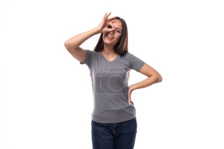 Téléchargez les photos : Jeune femme brune bien entretenue dans un t-shirt gris avec une maquette pour une identité sur un fond blanc avec espace de copie. - en image libre de droit
