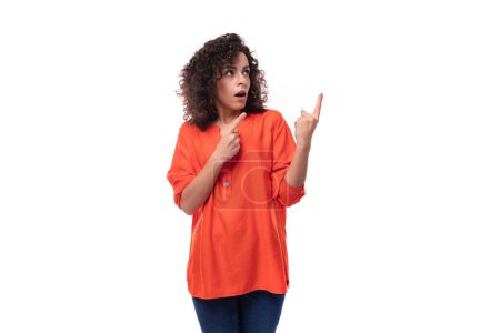 Téléchargez les photos : Jeune femme brune frisée vêtue d'un chemisier orange s'inspire d'une idée. concept de brainstorming. - en image libre de droit