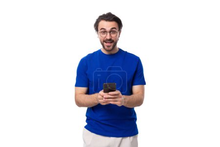Foto de Un tipo brutal europeo de 30 años con cabello negro y barba usa un teléfono móvil. - Imagen libre de derechos