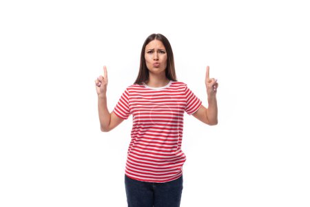 Téléchargez les photos : Jeune femme brune heureuse et satisfaite dans un t-shirt rayé gesticulant activement sur un fond blanc avec espace de copie. - en image libre de droit