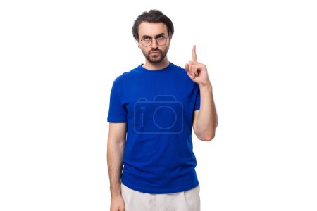 Téléchargez les photos : Jeune homme brune beau avec une barbe dans un t-shirt couleur entreprise. - en image libre de droit