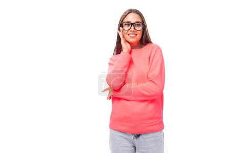 Téléchargez les photos : Mignon heureux mince jeune femme brune européenne vêtue de sweat-shirt rose sur fond isolé avec espace de copie. - en image libre de droit