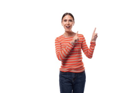 Foto de Una mujer guapa de 30 años, vestida con un suéter naranja casual, señala con sorpresa sus dedos. - Imagen libre de derechos