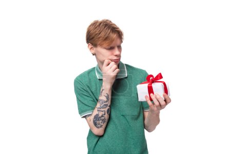 Foto de Un joven europeo de pelo rojo piensa lo que le dieron en una caja con una cinta. - Imagen libre de derechos