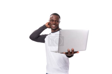 Foto de Chico africano joven con corte de pelo corto está utilizando el ordenador portátil para el trabajo remoto. - Imagen libre de derechos