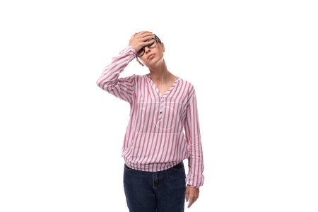 young office worker woman dressed in a pink white blouse and jeans holding her head.