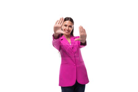 jeune employée de bureau femme aux cheveux noirs vêtue d'une veste rose semble heureuse.