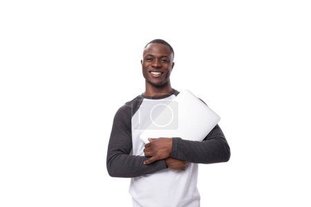 young african man working remotely in IT field and holding nuotbook on white background.