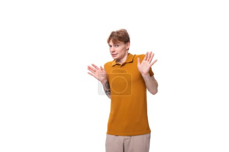 young caucasian man with red hair is dressed in a yellow t-shirt on a studio background.