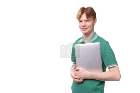 junger intelligenter erfolgreicher Student mit roten Haaren, der einen Laptop hält.