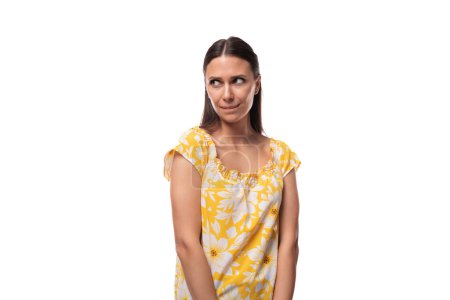 Foto de Joven bonita morena mujer vestida en un verano amarillo camiseta dudas. - Imagen libre de derechos