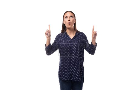 young cheerful cute caucasian brunette lady dressed in a dark blue blouse looks up and points her finger.