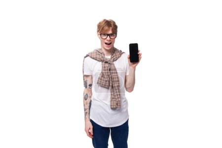 Porträt eines jungen rothaarigen Mannes mit Brille und Smartphone in der Hand. Werbekonzept.