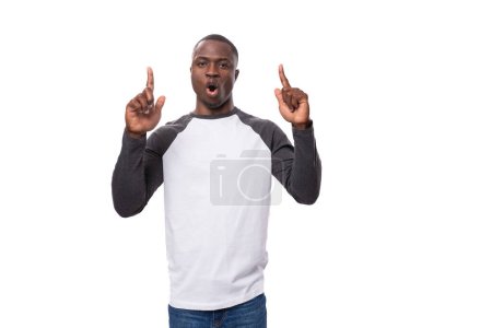 Foto de Un joven americano con un corte de pelo corto, vestido con un suéter de manga larga, cuenta la noticia con sorpresa. - Imagen libre de derechos