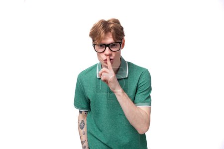portrait of a young man with red hair dressed in a green T-shirt keeping a secret.