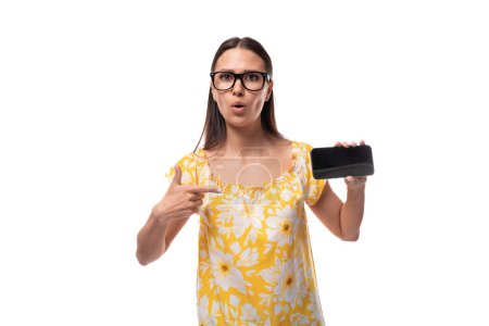 jeune jolie femme caucasienne dans un t-shirt jaune d'été montre soigneusement un smartphone avec une disposition horizontale.