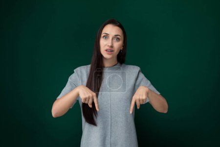 A woman with long hair is pointing towards a specific direction or object, indicating interest or significance. Her gesture suggests she is drawing attention to something noteworthy or important.