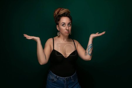 Photo for A woman wearing a black top stands with her hands outstretched in front of her. She appears to be expressing a gesture of openness or seeking connection. The background is plain and nondescript. - Royalty Free Image