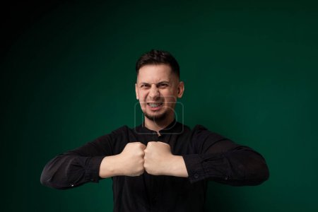 A man wearing a black shirt is shown in the act of making a fist gesture, showcasing determination or readiness for action.
